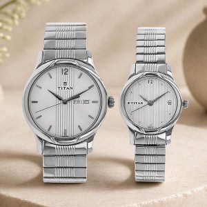 Pair of Titan silver wristwatches (men’s and women’s) with metal link bands and striped dials on a beige surface.