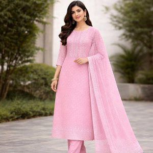 Woman in a pink embroidered salwar kameez with matching dupatta, standing outdoors.