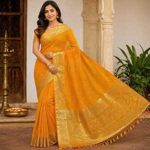 Woman in a bright orange saree with gold borders, posing at a temple-style doorway.